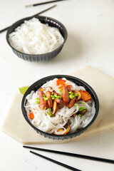 Bowl with tasty rice noodles and meat on white background