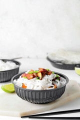 Bowl with tasty rice noodles and meat on white background