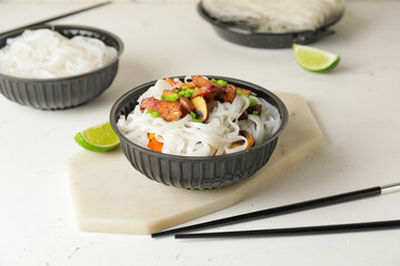 Bowl with tasty rice noodles and meat on white background