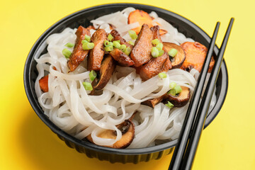 Bowl with tasty rice noodles and meat on color background