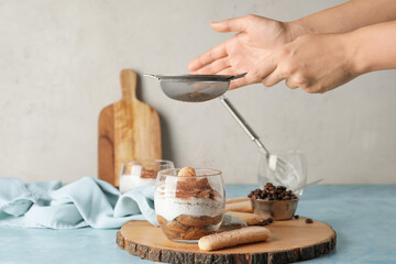 Woman making tasty tiramisu at home
