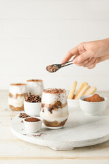 Woman making tasty tiramisu at home