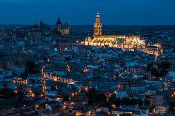 Fototapeta na wymiar Vista de la ciudad de Toledo, España, al anochecer, con las luces iluminando la Catedral. Vista desde el Parador Nacional, en la otra orilla del río Tajo.