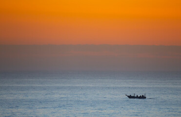 A fisherman boat in the peaceful sea at sunset.