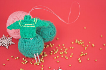 Christmas handicraft and needlework concept.knitting needles and green and pink balls of yarn in red background.Holiday New Year greeting card.