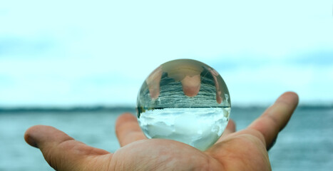 crystal glass earth. close up hand holding glass global with  sea. empty copy space background, world environment day, hello summer. season concept