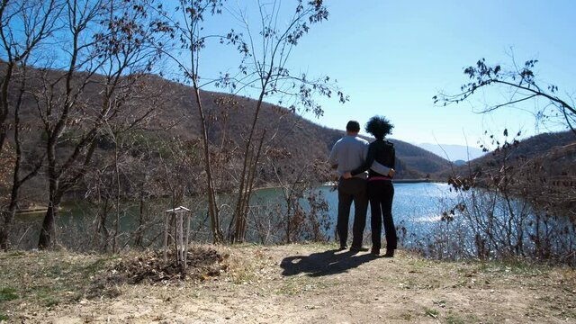 sweet romantic couple standing and hugging in the park with view to the lake