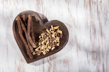 Licorice root in bowl on wooden background