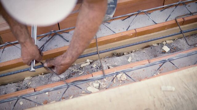 Closeup shot of worker apllying steel bar reinforcement used for reinforcing concrete slab