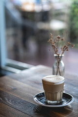 Latte served on a glass over a wooden table on cafeteria
