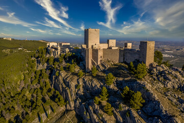 Dreamy cloudy sky above Jaen medieval Gothic castle and parador on an outcrop of a steep hill towering over the largest olive grove in the world - obrazy, fototapety, plakaty