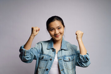 Asian woman happy confident standing showing her fist make a winning gesture isolated over white background.