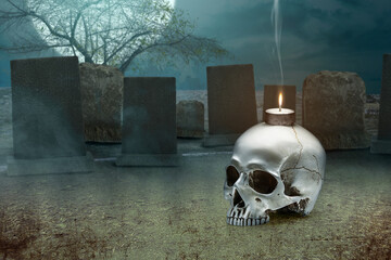 Human skull with a burning candle on the graveyard