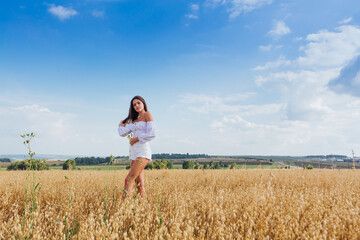 Young beautiful woman relaxing at golden oat field.