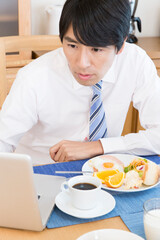 Fototapeta na wymiar 食事しながらノートパソコンをする男性
