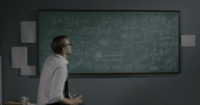 Smart mathematician reviewing math formulas on the chalkboard