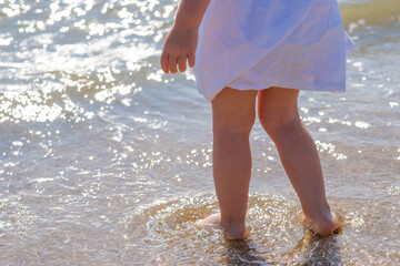 Small baby feet close-up on the sand of the sea beach. Sea water washes the feet. Happy childhood. Rest at the sea. Summer sunny day. Copy space.