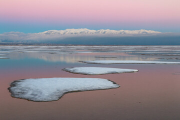 Rare frozen saltwater at the Great Salt Lake in Northern Utah. Wasatch Mountains in the distance at sunset, Utah in Winter.