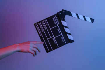 Hand touches film clapper board in blue red neon light. Cinema industry, entertainment. Concept...