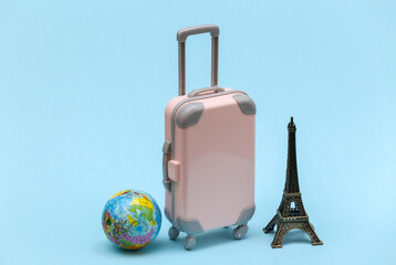 Traveled to Paris. Mini plastic travel suitcase and statuette of the Eiffel Tower, globe on blue background.