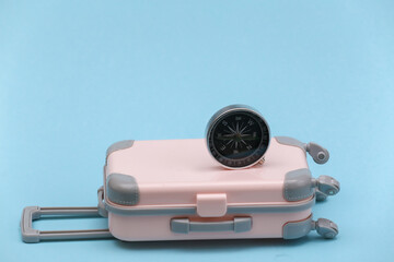 Travel or trip concept. Mini plastic travel suitcase and compass on blue background. Minimal style