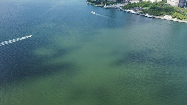 A Bird's Eye View Directly Over Upper Bay With Two Boats Sailing By. The Clouds Cast Their Shadows Onto The Waters Below. The Drone Dolly In And Tilts Up To Reveal Lower Manhattan. It Is A Sunny Day