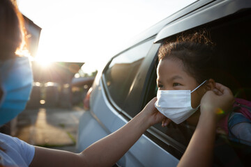 Asian mother help her daughter wearing protection mask to protect the coronavirus Covid-19 outbreak...