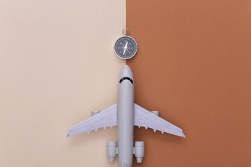 Minimalism travel flat lay. Compass and air plane on beige brown background. Top view
