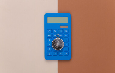 Calculator and compass on beige brown background. Business concept. Top view