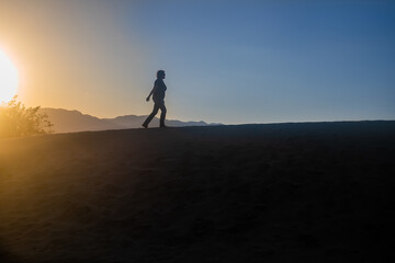 Fototapeta na wymiar silhouette of a woman climbing a desert hill in a sunset