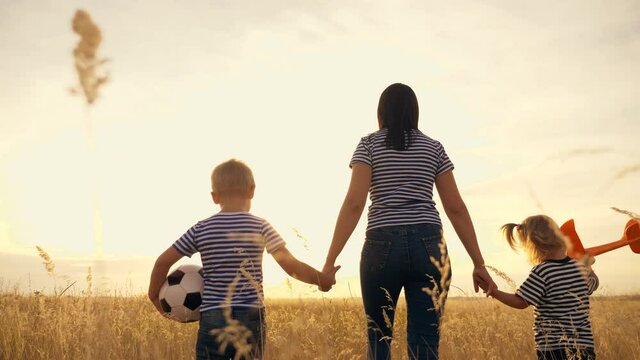 Happy family in the park. Mom and kids are walking in the park at sunset with an airplane and a ball. Kids dream of victories and flights. Dream to be an airplane pilot. Happy family concept. Football