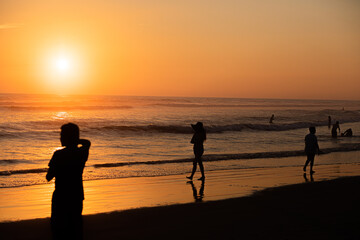 silhouette of people at the edge of the sea in a sunset