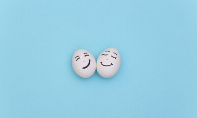 Happy loving couple of chicken eggs faces on blue background