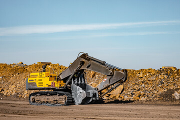 Yellow excavator steel bucket working on construction open mining site © Parilov