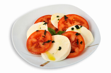 Delicious tomato salad with feta cheese on a plate isolated on a white background. Selective focus.