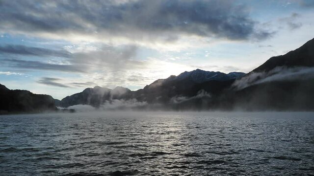 Maloja mountain Pass, Switzerland. Landscape of the lake Sils in the morning during the fall time. The fog covers the lake and the shores. Traditional Swiss contest. Natural landscape