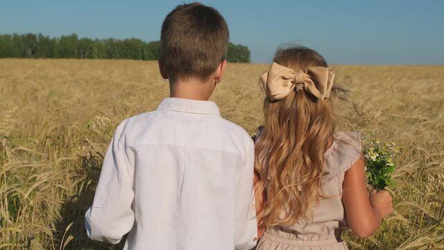Happy family. Little cute boy and girl holding hands playing walking through wheat field meadow summer nature. first love, friendship, childhood concept. Funny kids, child. lovely children 4 K slow-mo