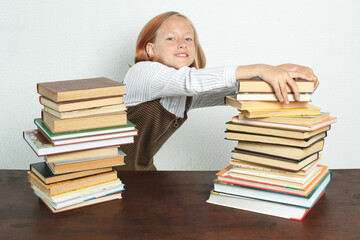A teenage girl takes books from a stack of books on the table.
