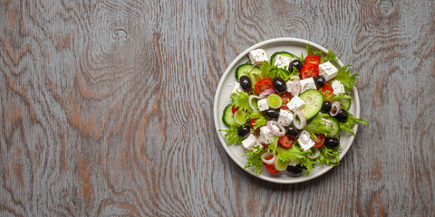 Greek salad of fresh cucumber, tomato, sweet pepper, lettuce, red onion, feta cheese and olives with olive oil. Healthy food, top view