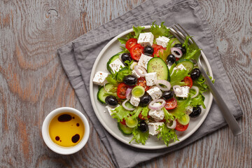 Greek salad of fresh cucumber, tomato, sweet pepper, lettuce, red onion, feta cheese and olives with olive oil. Healthy food, top view