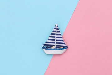 Sailboat on a blue pink background. Travel minimalism concept. Top view. Flat lay