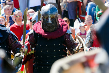 Fototapeta na wymiar Medieval restorers fight with swords in armor at a knightly tournament