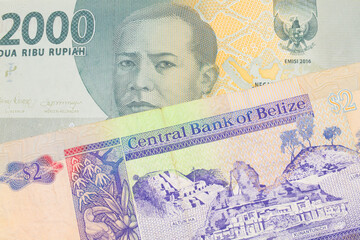 A macro image of a grey two thousand Indonesian rupiah bank note paired up with a colorful two dollar bill from Belize.  Shot close up in macro.