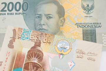 A macro image of a grey two thousand Indonesian rupiah bank note paired up with a colorful, plastic quarter dinar from Kuwait.  Shot close up in macro.