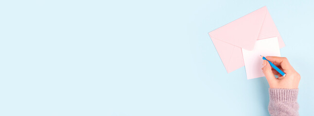 Hand with pencil and letter with envelope, writing mail, isolated on blue background, copy space template, banner.
