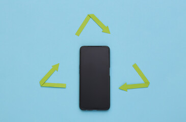 Recycled arrows sign and smartphone on blue background. Top view