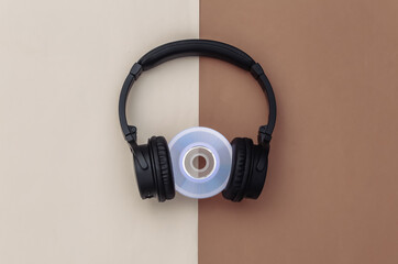 Stereo headphones with cd disk on brown beige background. Top view