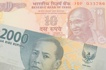 A macro image of a grey two thousand Indonesian rupiah bank note paired up with a orange ten rupee bill from India.  Shot close up in macro.