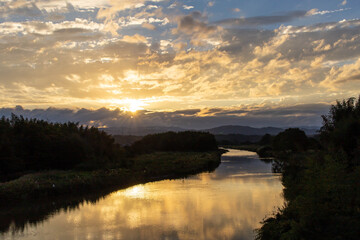 田園地帯の川に映り込む朝焼け