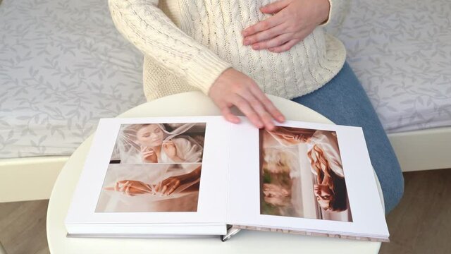 close up. couple waiting for baby flips through photo book from wedding.